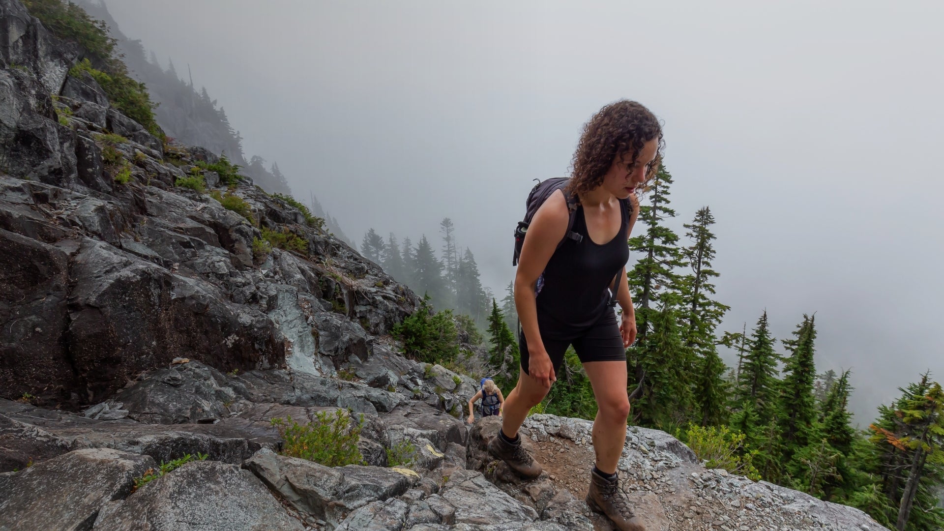 Person hiking on a rocky mountain trail with foggy background